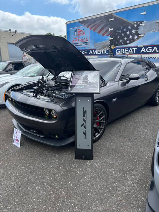 Car with open hood at a dealership, featuring a display stand.