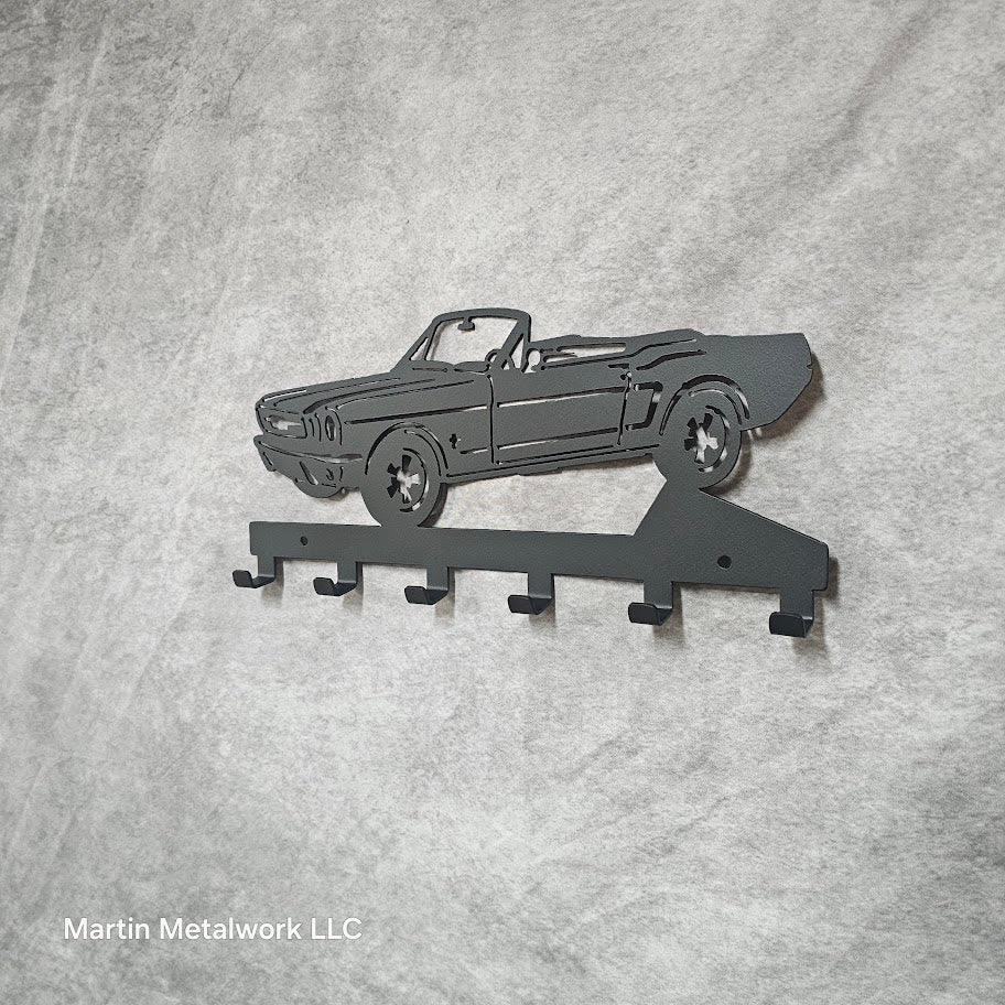 Metal key holder shaped like a classic car on a gray background