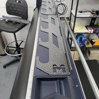 Modular wall-mounted tint rack segments with a central split, designed for customizable installation, displayed on a large format printer indicating the rack's adaptability and space-saving features in a professional setting.